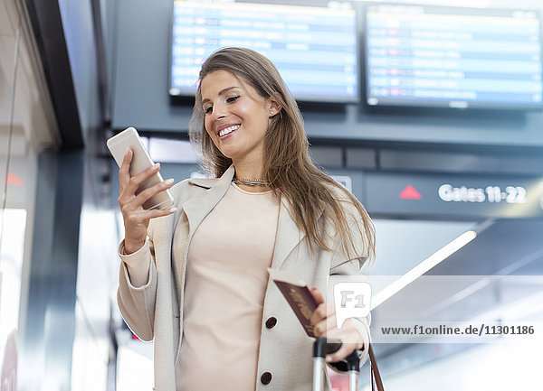 Geschäftsfrau mit Reisepass mit Handy am Flughafen