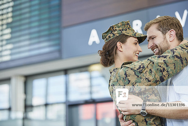 Ehemann begrüßt und umarmt Soldatenfrau am Flughafen