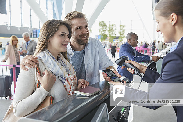 Kundendienstmitarbeiter scannt Smartphone QR-Code am Check-in-Schalter am Flughafen