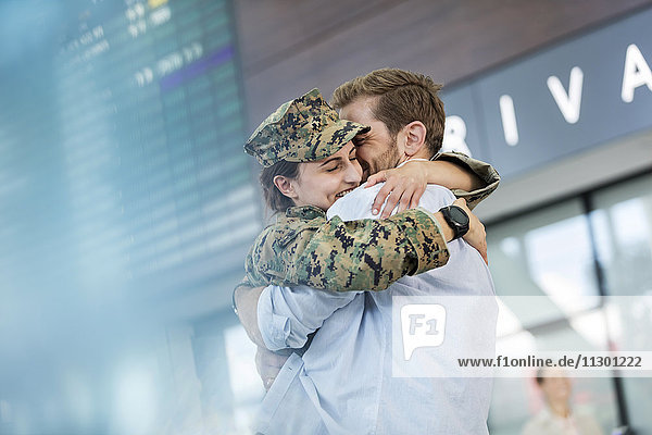 Ehemann begrüßt und umarmt Soldatenfrau am Flughafen
