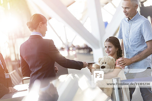 Flugbegleiterin überprüft Ticket des Mädchens mit Teddybär im Flughafen
