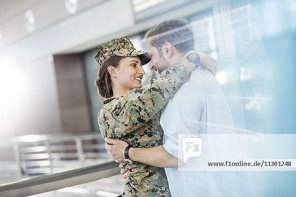 Ehemann grüßt umarmende Soldatenfrau am Flughafen