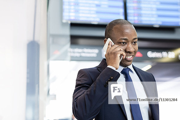 Geschäftsmann beim Telefonieren am Flughafen