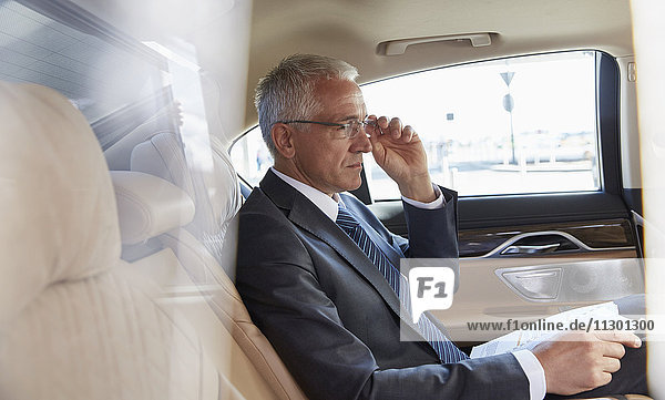 Geschäftsmann mit Papierkram auf dem Rücksitz des Stadtautos