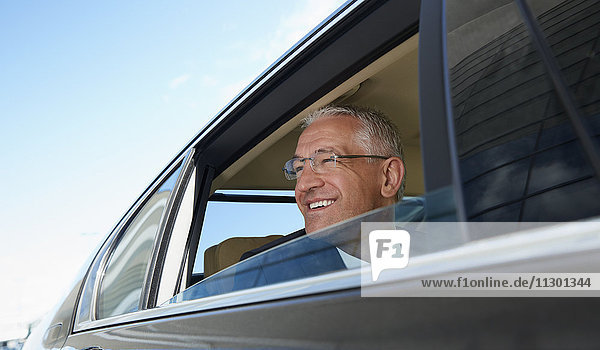 Lächelnder Geschäftsmann schaut aus dem Stadtautofenster