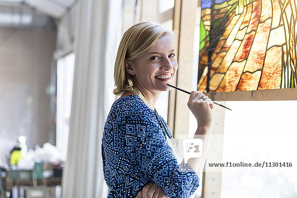 Portrait lächelnder Künstler bei der Arbeit an Glasmalerei