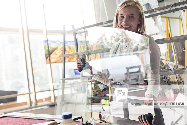 Portrait lächelnder Glasmaler beim Heben von Glas im Atelier
