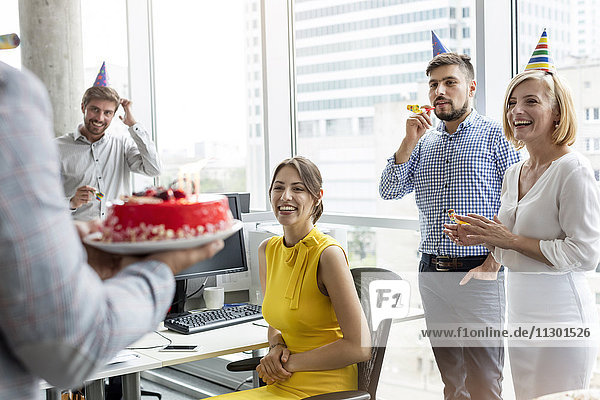 Geschäftsleute feiern Geburtstag mit Kuchen im Büro
