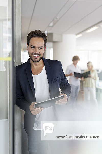 Portrait lächelnder Geschäftsmann mit digitalem Tablett im Büro