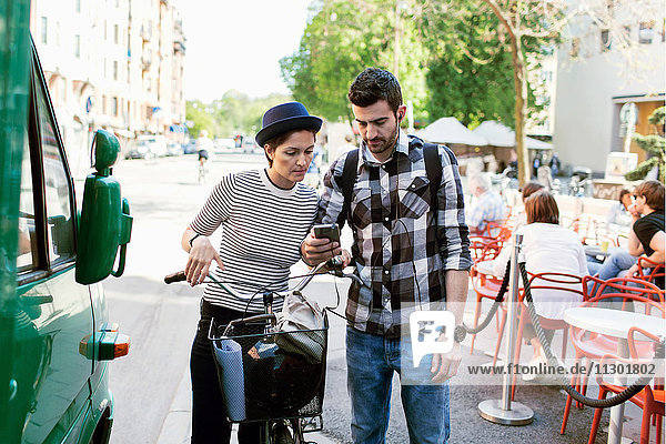 Paar mit Smartphone im Stehen am Bürgersteig Cafe