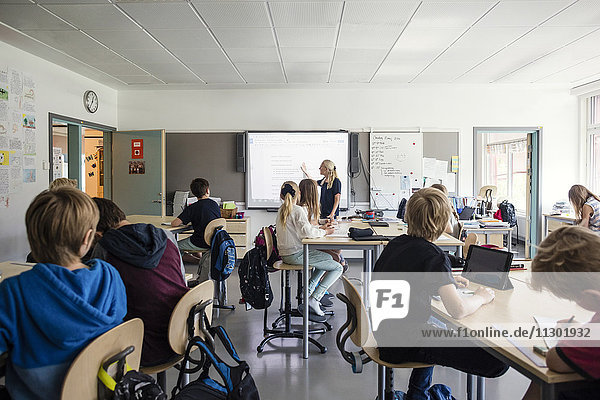 Teacher explaining students through whiteboard in classroom