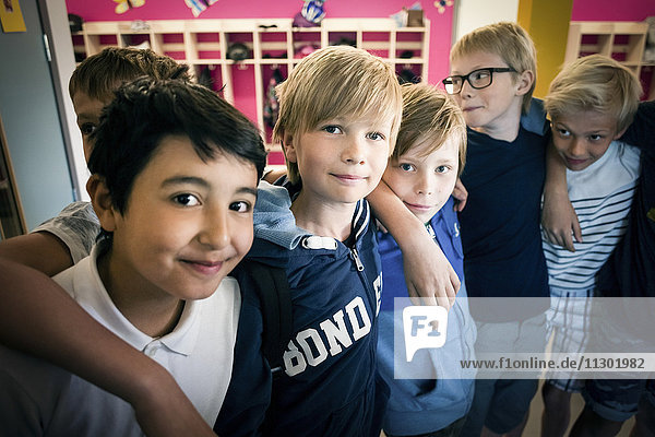 Porträt von glücklichen Jungen  die im Schulflur stehen
