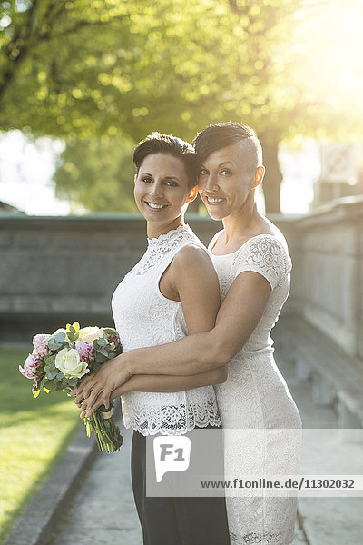 Portrait eines jungvermählten lesbischen Paares mit Blumenstrauß im Park