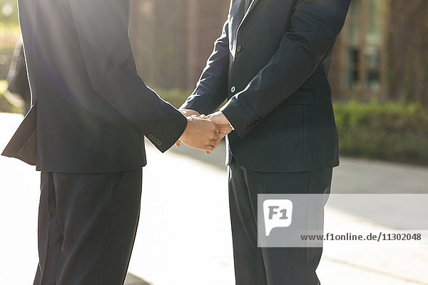 Mittelteil eines frisch verheirateten schwulen Paares  das Händchen hält.