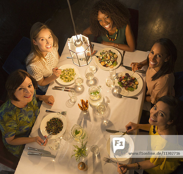 Portrait lächelnde Freundinnen beim Essen am Restauranttisch