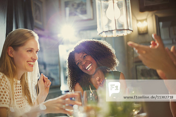 Lachende Frauenfreunde beim Klatschen und Essen am Restauranttisch