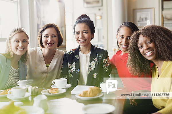 Portrait lächelnde Freundinnen beim Kaffeetrinken am Restauranttisch