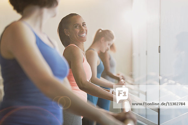 Smiling women at barre in exercise class gym studio