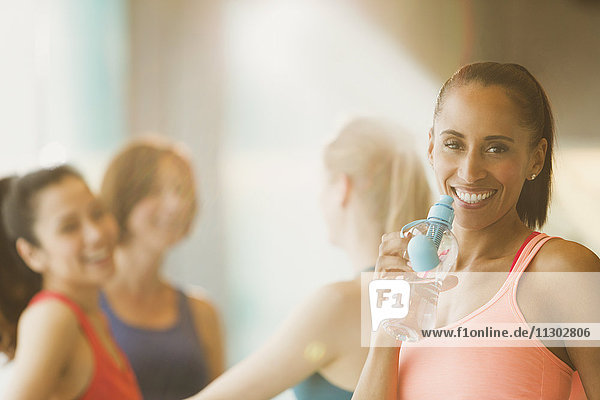 Portrait smiling woman drinking water in exercise class gym studio