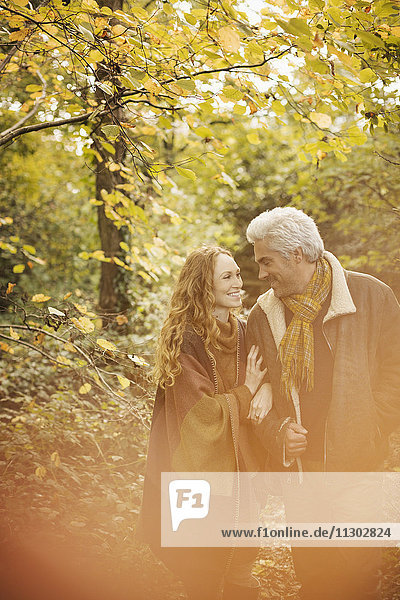 Zärtliches Paar spaziert Arm in Arm im Herbstwald