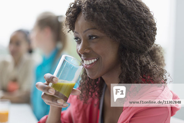 Lächelnde Frau trinkt gesunden grünen Smoothie in Cafe Post Workout
