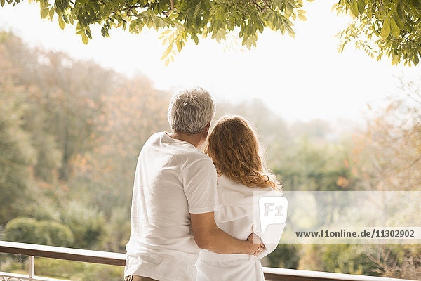 Zärtliches Paar umarmt Blick auf Herbst Bäume auf der Terrasse