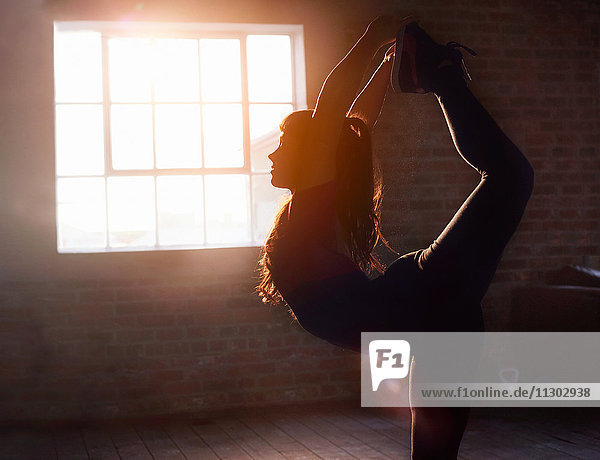 Silhouette Tänzerin Stretching praktizierende Yogakönigstänzerin Pose im Studio