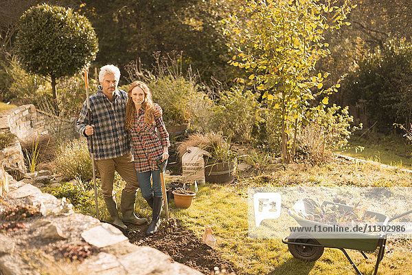 Portrait lächelndes Paar bei der Gartenarbeit im sonnigen Herbstgarten