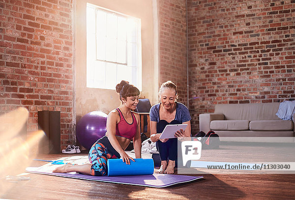 Fitnesstrainerin und junge Frau mit digitalem Tablett im Fitness-Studio