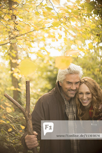 Portrait lächelndes Paar mit Spazierstock im Herbstwald