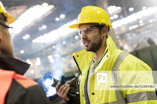 Steel workers talking in factory