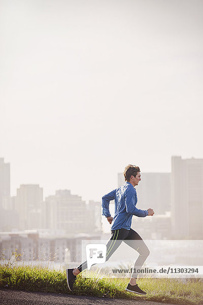 Männlicher Läufer  der auf einer sonnigen städtischen Straße läuft