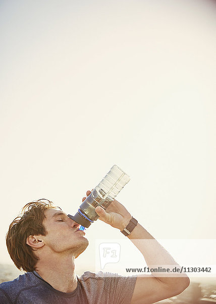 Durstiger männlicher Läufer  der Wasser aus einer Wasserflasche trinkt
