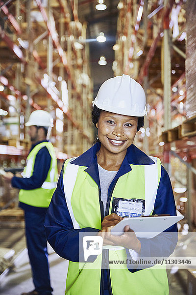 Portrait confident female manager with clipboard in distribution warehouse