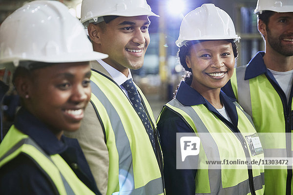 Portrait confident female worker with coworkers in distribution warehouse