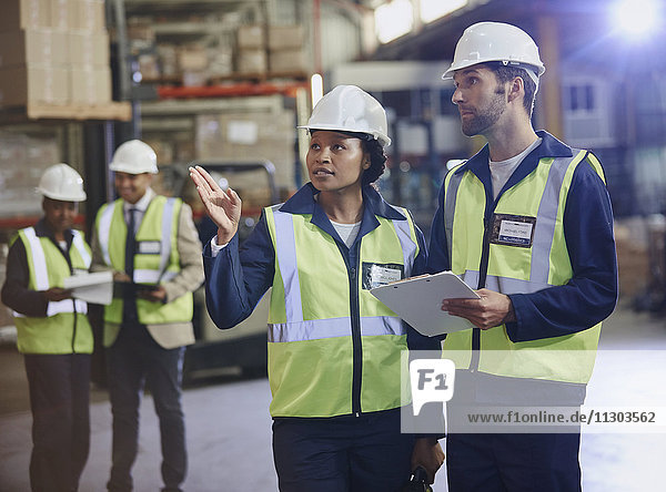 Workers with clipboard talking in distribution warehouse