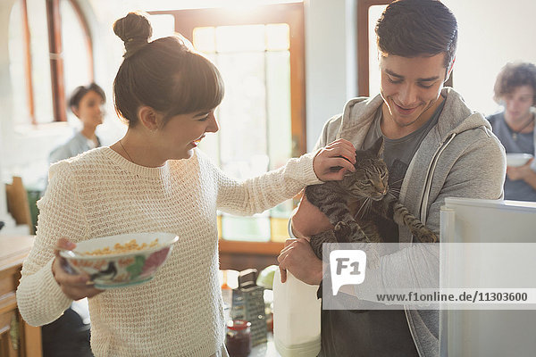 Young couple petting cat in kitchen