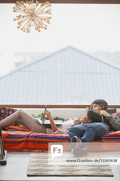 Junges Paar entspannt mit Laptop am Fenster