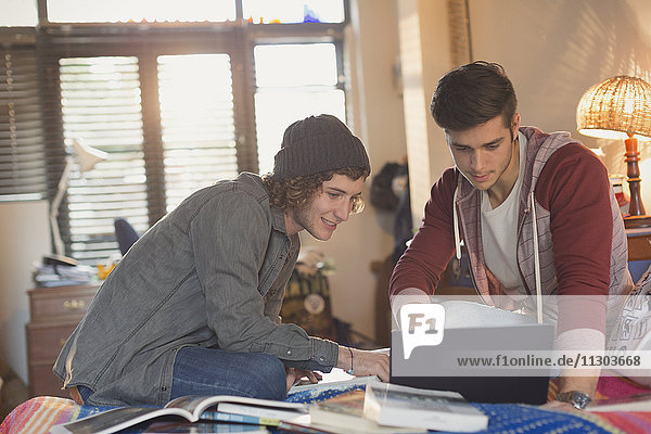 Young men college students studying using laptop
