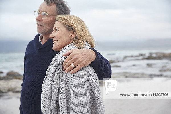 Affectionate senior couple hugging on winter beach