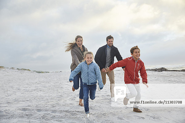 Verspielte Familie beim Laufen am Winterstrand