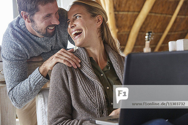 Glückliches Paar lachend und mit Laptop