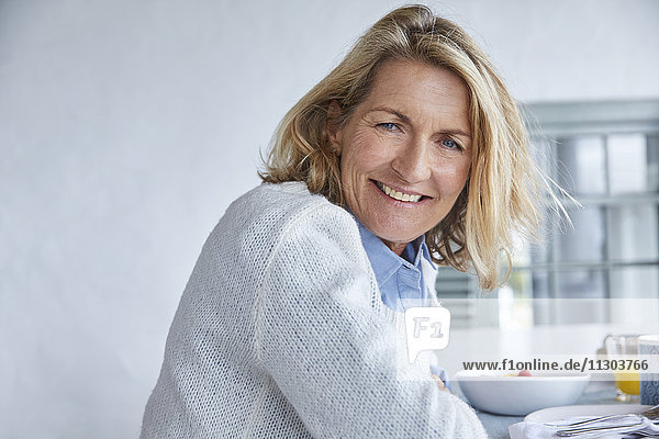 Porträt lächelnde ältere Frau beim Frühstück auf der Terrasse