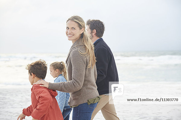 Portrait smiling family walking on winter beach