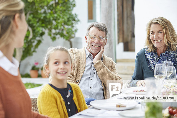 Mehrgenerationenfamilie beim Mittagessen am Terrassentisch