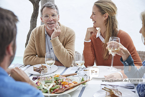 Paare trinken Weißwein und essen zu Mittag am Terrassentisch