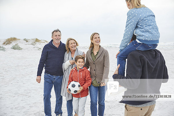 Mehrgenerationenfamilie mit Fußball am Winterstrand