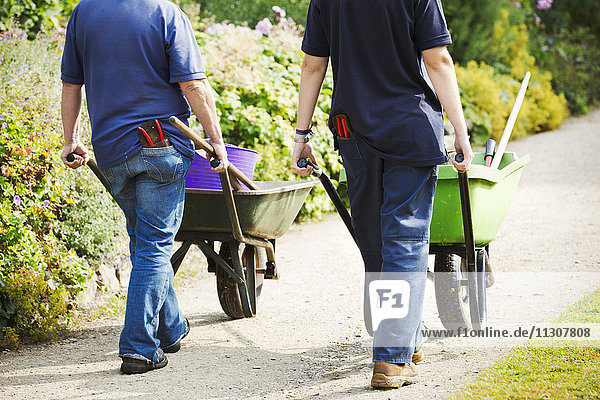 Two gardeners pushing wheelbarrows at Waterperry Gardens in Oxfordshire.