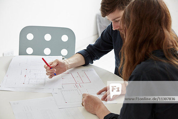 Ein modernes Büro. Zwei Personen bei einem Treffen  bei dem Pläne und Zeichnungen diskutiert werden  Architekturzeichnungen.