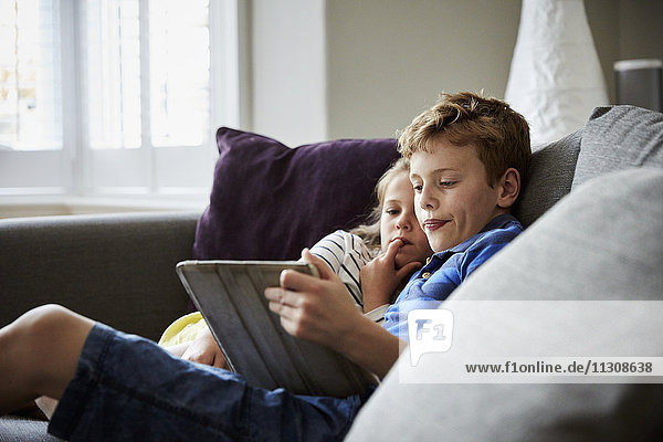 Zwei sitzende Kinder teilen sich ein digitales Tablett und schauen auf den Bildschirm.